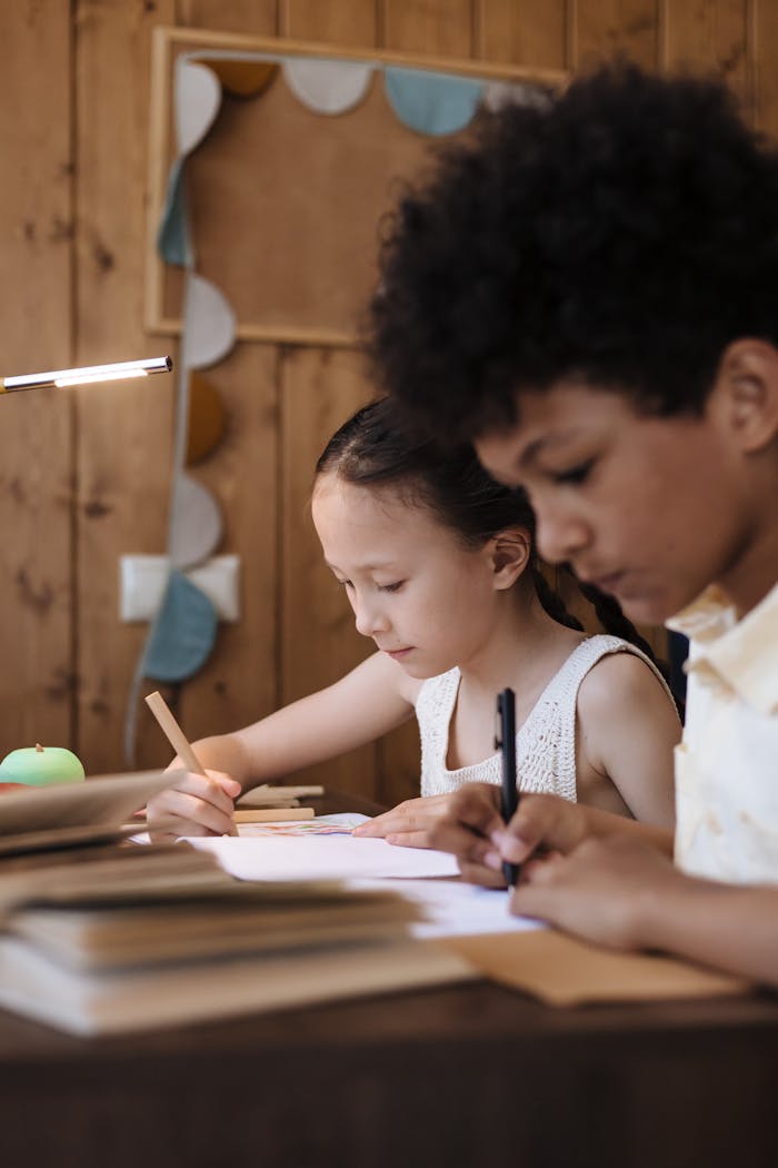 Two kids focusing on writing tasks together in a cozy indoor setting, promoting learning.